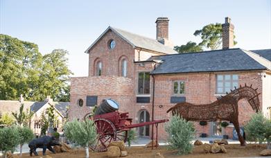 The exterior of the fuel tank restaurant, as well as the surrounding buildings and statue of a metal horse pulling a wagon.