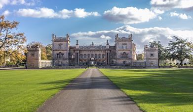 A view of Grimsthorpe Castle, with a long driveway leading to the main house