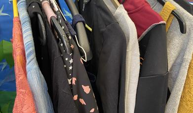 A selection of clothes hanging on a rail at a previous Clothes Swap event hosted by Lincoln Sustainable Fashion Forum. T-shirts, jumpers and jackets h