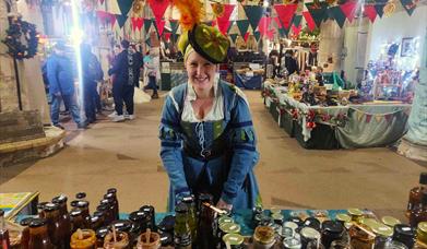 A woman, dressed in medieval costume, at a medieval market.
