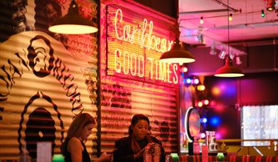The colourful interior of Turtle Bay in Lincoln, with a neon sign saying Caribbean Good Times in the background
