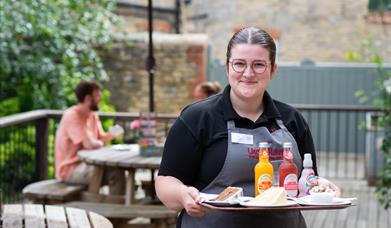 Image shows a waitress serving a couple a tray of food and drink at Uncle Henry's Farm Shop & Cafe