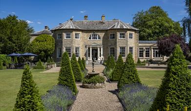The view of Washingborough Hall Hotel, a symmetrical mansion, surrounded by beautiful gardens.